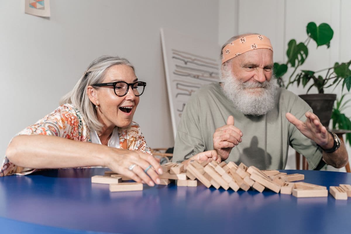 Twee ouderen spelen samen een spel met houten blokjes aan een tafel