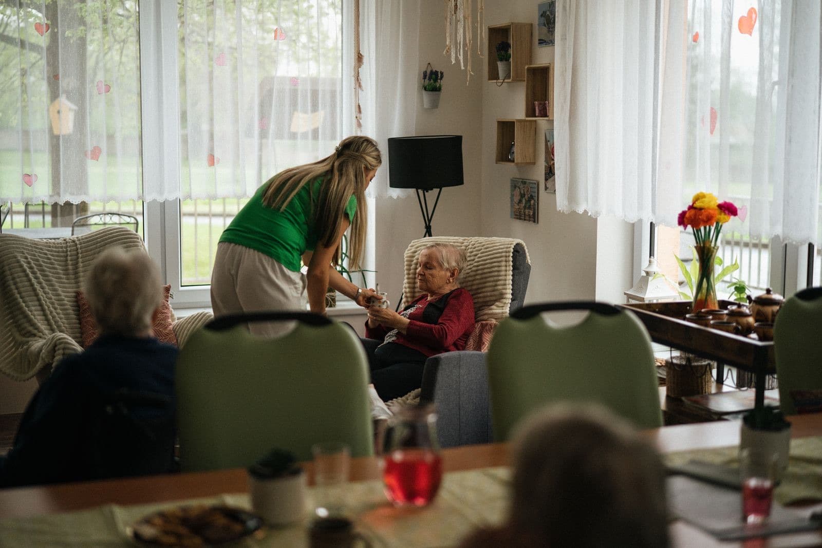 Een zorgverlener brengt een oudere vrouw thuis een kopje thee